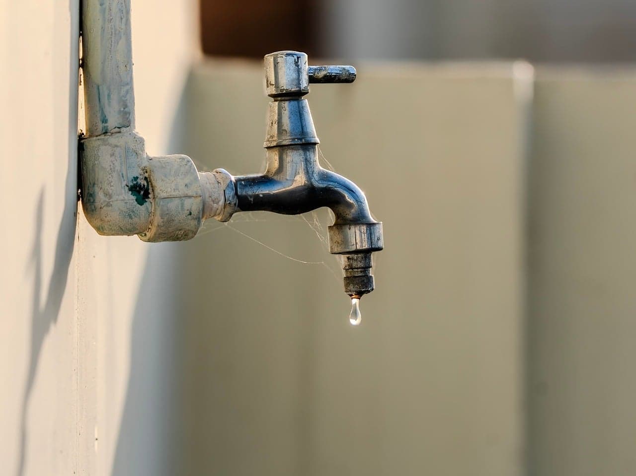 A drop of water about to fall from an old tap